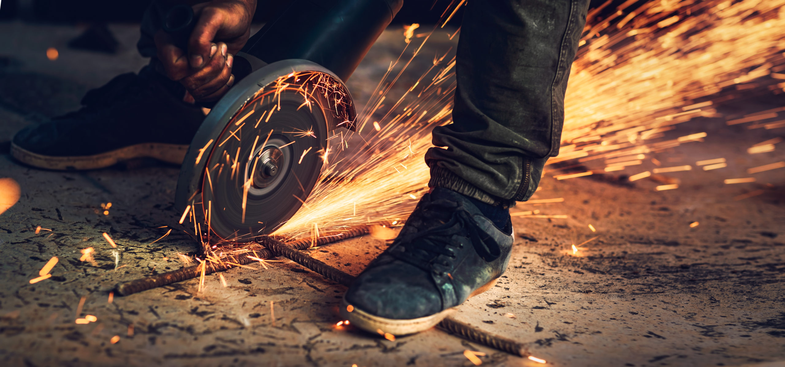 Welder in action, close up photo of hot bright sparks that fly out from under the saw, portable steel cutting machine, hard work, necessary occupation, blue-collar worker, panoramic photo format